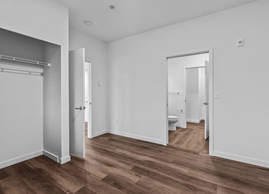 a bedroom with white walls and a bathroom with a toilet and a closet