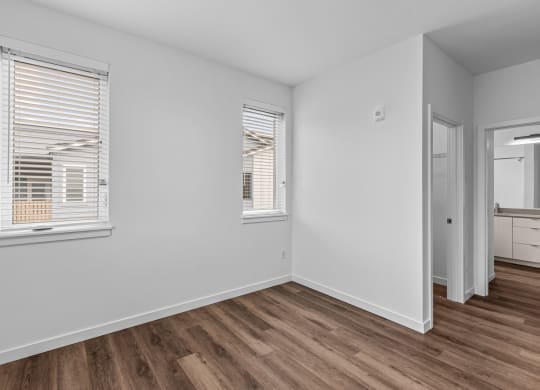 the living room of an apartment with white walls and wood flooring
