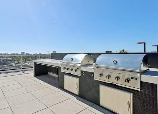 A row of outdoor grills on a rooftop patio.
