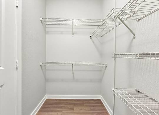 Empty white walk in closet with shelves.