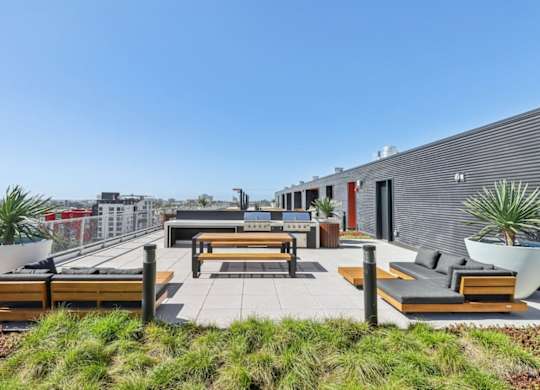 A rooftop patio with benches and plants.