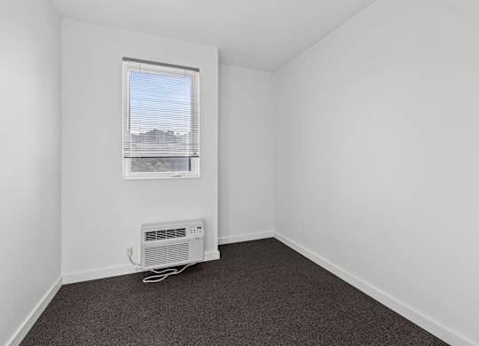 A room with a window and a fan on the floor.