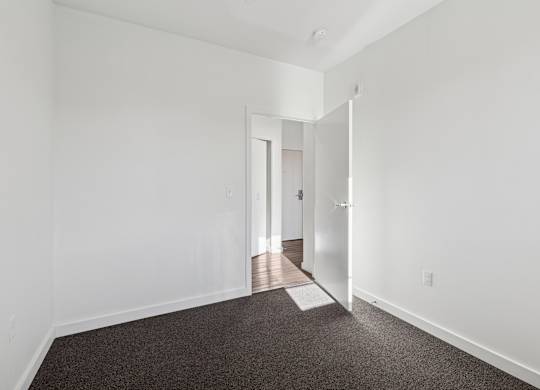 A hallway with a carpeted floor and white walls.