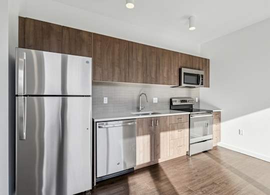 A modern kitchen with a stainless steel refrigerator and wooden cabinets.