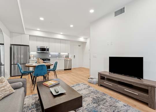 OnyxOnPark_SanDiego_CA_Model_1BR_ A modern living room with a grey sofa, a wooden coffee table, and a black television.