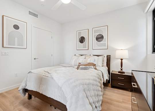 OnyxOnPark_SanDiego_CA_Model_1BR_ A bedroom with a large bed and two framed pictures on the wall.