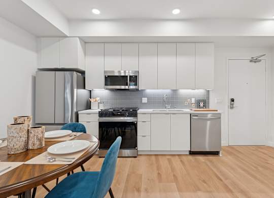 OnyxOnPark_SanDiego_CA_Model_1BR__A modern kitchen with a dining table set for two.