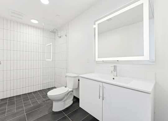 OnyxOnPark_SanDiego_CA_Vacant_2BR_ A white bathroom with a toilet, sink, and mirror.