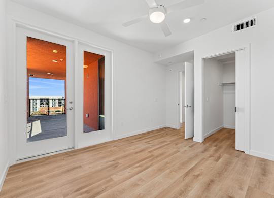 OnyxOnPark_SanDiego_CA_Vacant_2BR_B1_A room with a ceiling fan and a door leading outside.