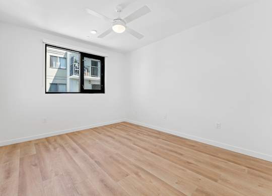 OnyxOnPark_SanDiego_CA_Vacant_Penthouse_A_A room with a ceiling fan and a window showing a building outside.