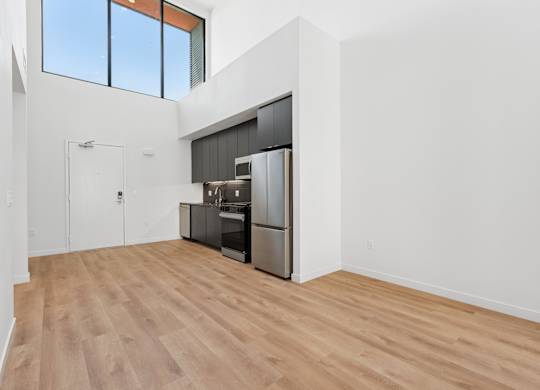 OnyxOnPark_SanDiego_CA_Vacant_Penthouse_A_OnyxOnPark_SanDiego_CA_Vacant_Penthouse_A_A kitchen with a refrigerator, oven, and sink is in a room with wooden floors and white walls.