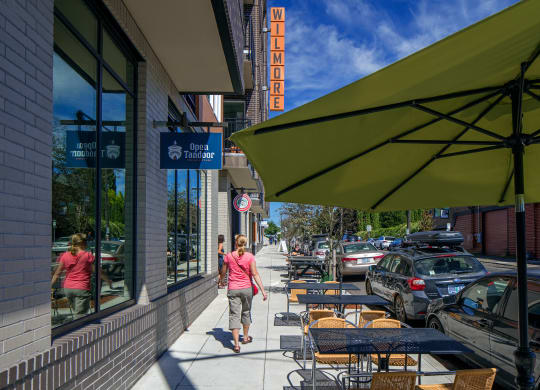 a woman walking down a sidewalk in front of a restaurant