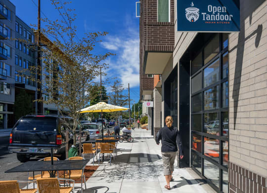 a man walking down a sidewalk in front of a restaurant