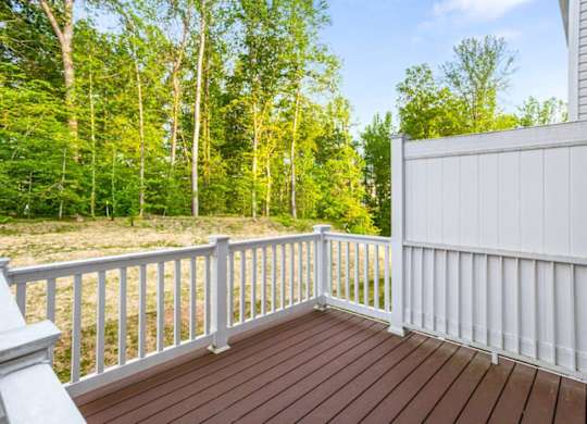 A deck with a white railing and a brown floor.