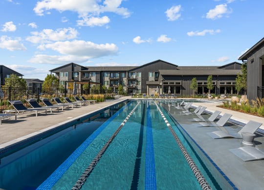 a swimming pool with lounge chairs and a building in the background