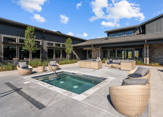 a patio with a pool and chairs in front of a building