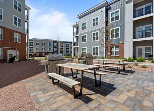 A wooden table and benches are set up in a courtyard with brick pavers.