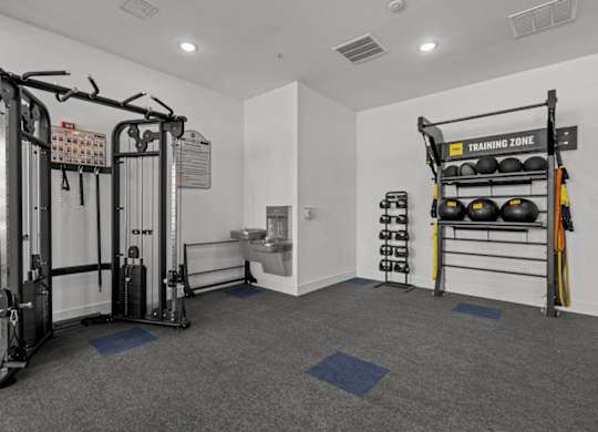 A gym with a weightlifting area and a rack of kettlebells.