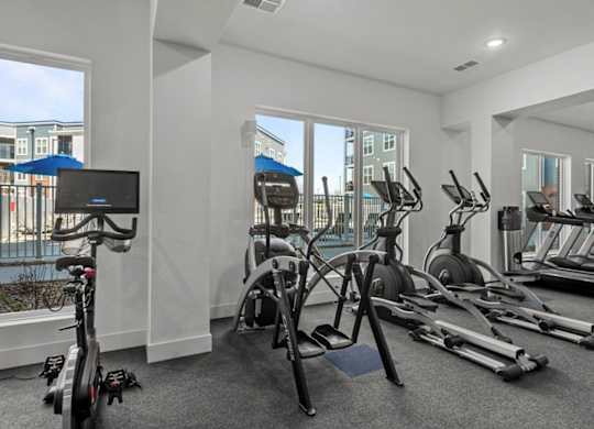 A gym with a row of treadmills and exercise bikes.