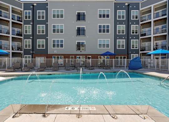 A large swimming pool in front of apartment buildings with a 4'6