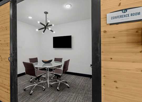 A conference room with a table and chairs and a sign on the wall.