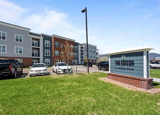 The Edison apartments are located in a grassy area with cars parked in the background.