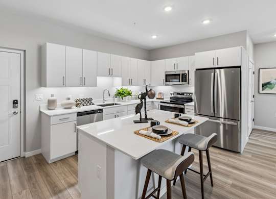 A modern kitchen with a white island and stainless steel appliances.