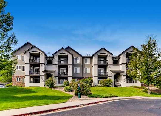A large apartment complex with multiple balconies and a green lawn in front.