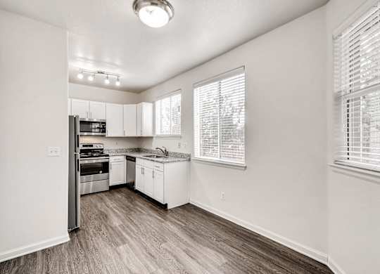 A kitchen with white cabinets and a wooden floor.
