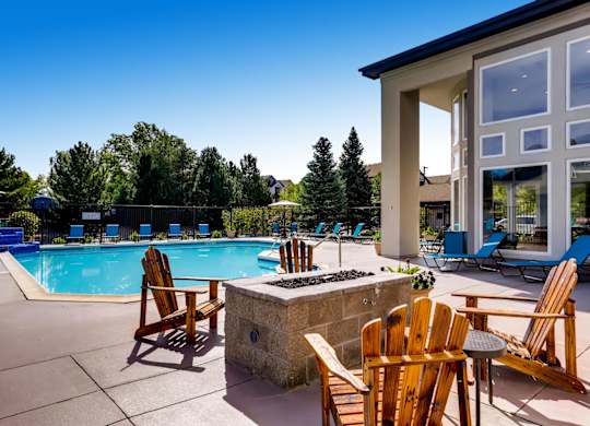A poolside area with chairs and a stone fireplace.