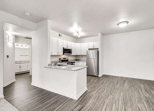 A kitchen with a refrigerator, microwave, and oven.