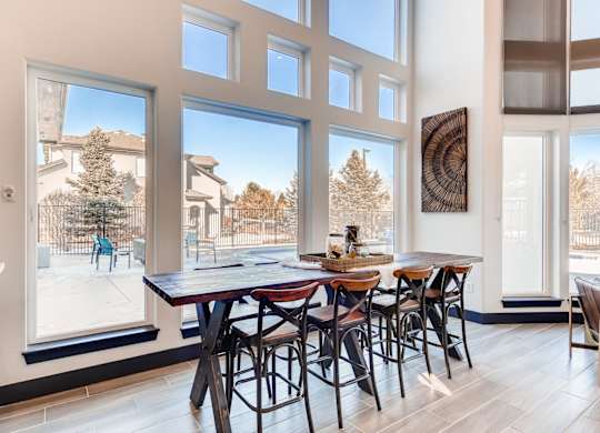 A dining room with a table and chairs in front of large windows.