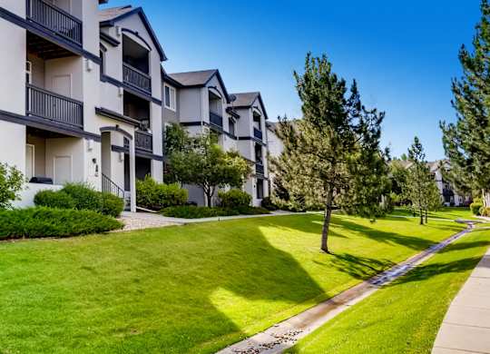 Apartment complex with green lawn and trees.