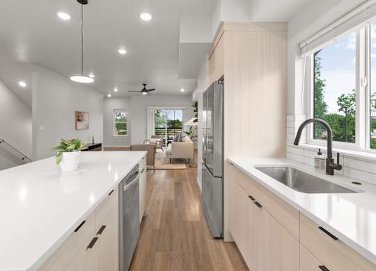 A modern kitchen with a long white countertop and stainless steel appliances.