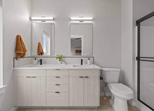 A white bathroom with a toilet, sink, and mirror.