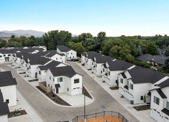A row of white houses with black roofs are lined up in a residential area.