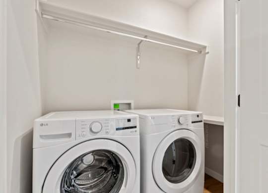 Two white washing machines in a small laundry room.