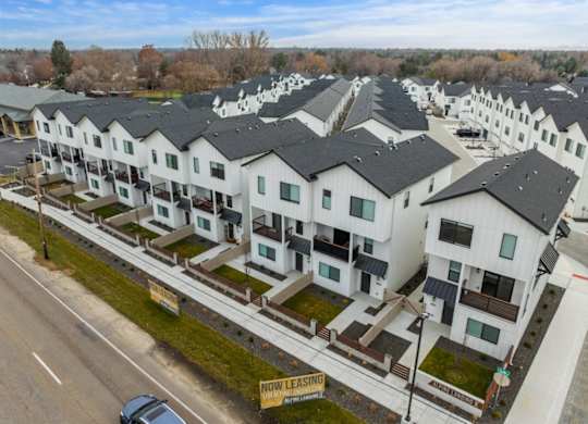 A row of white houses with a sign that says "Now Leasing" in front of them.
