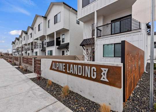 A sign that says Alpine Landing in front of a building.