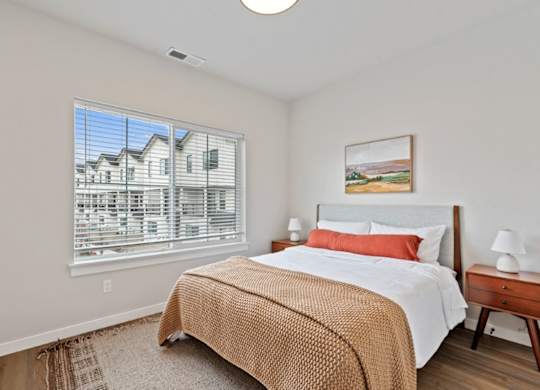 A bedroom with a large bed and a painting on the wall.