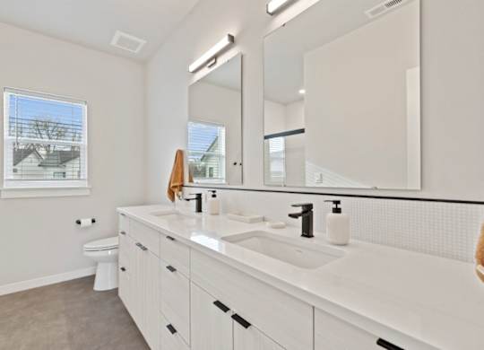 A bathroom with a white sink, toilet, and mirror.