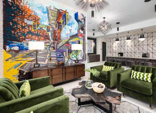 a living room with green couches and a colorful mural on the wall