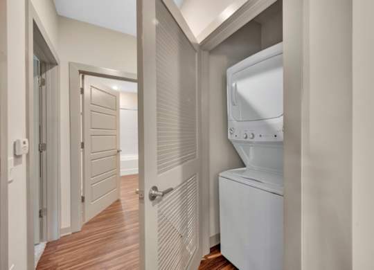 A white washing machine is in a narrow hallway.
