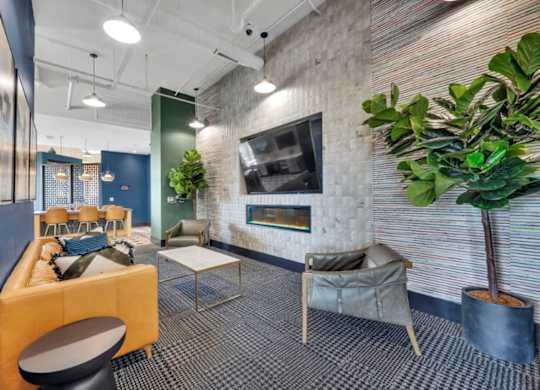 A modern office space with a yellow sofa, a grey armchair, and a potted plant.