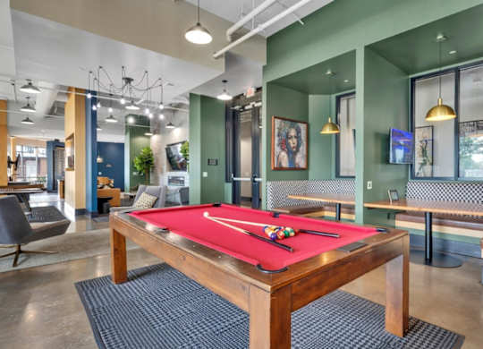 A pool table is in the middle of a room with a green wall.