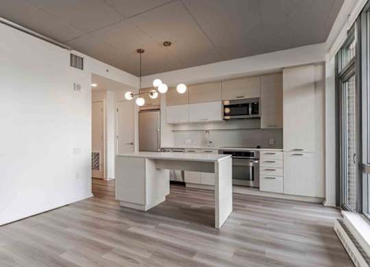 A modern kitchen with a white island and wooden floors.