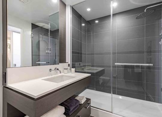 A modern bathroom with a white sink and a walk-in shower.