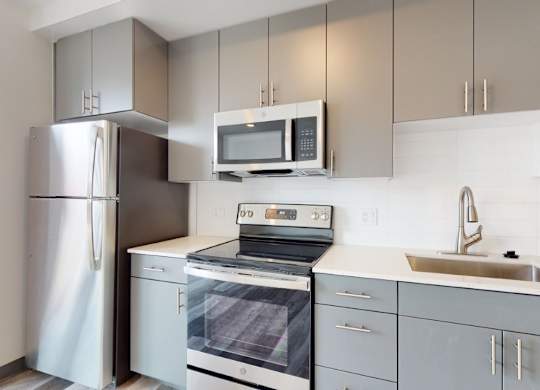 A modern kitchen with a stainless steel refrigerator, microwave, and dishwasher.
