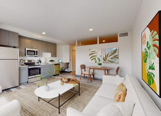 A modern kitchen with white appliances and a dining area with a white couch and a painting on the wall.