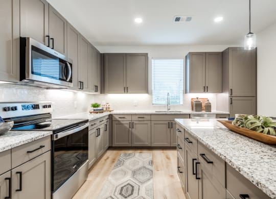 Aura 3Twenty Apartments open kitchen with granite counter tops and stainless steel appliances